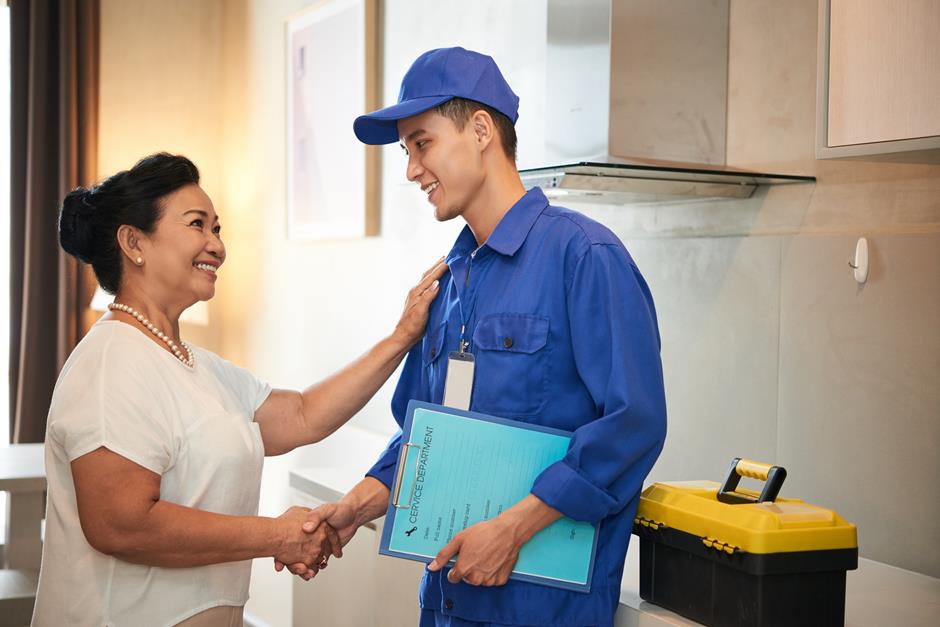 Técnico de uniforme cumprimenta a cliente depois do atendimento
